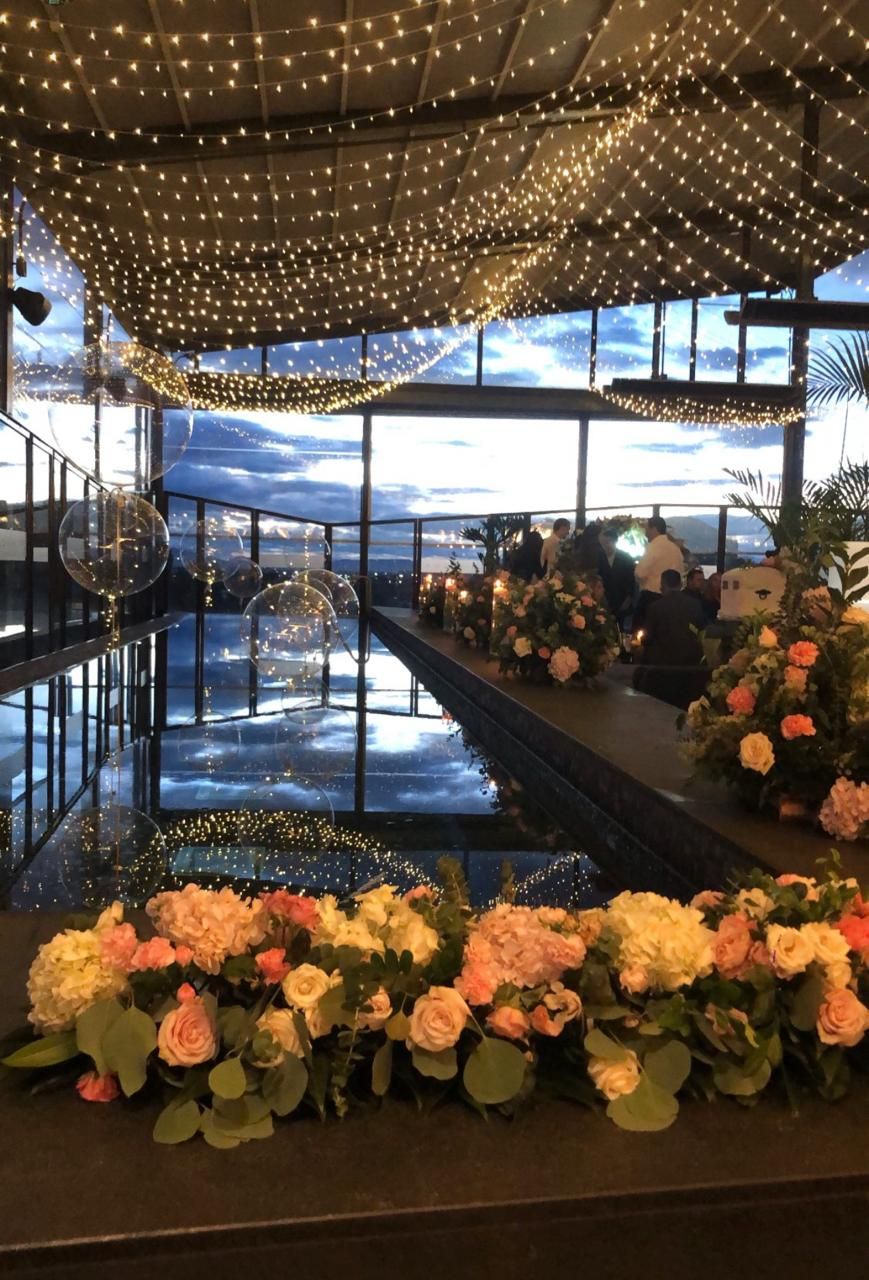 Terraza con vista a la ciudad, techo de luces y mesas decoradas con flores