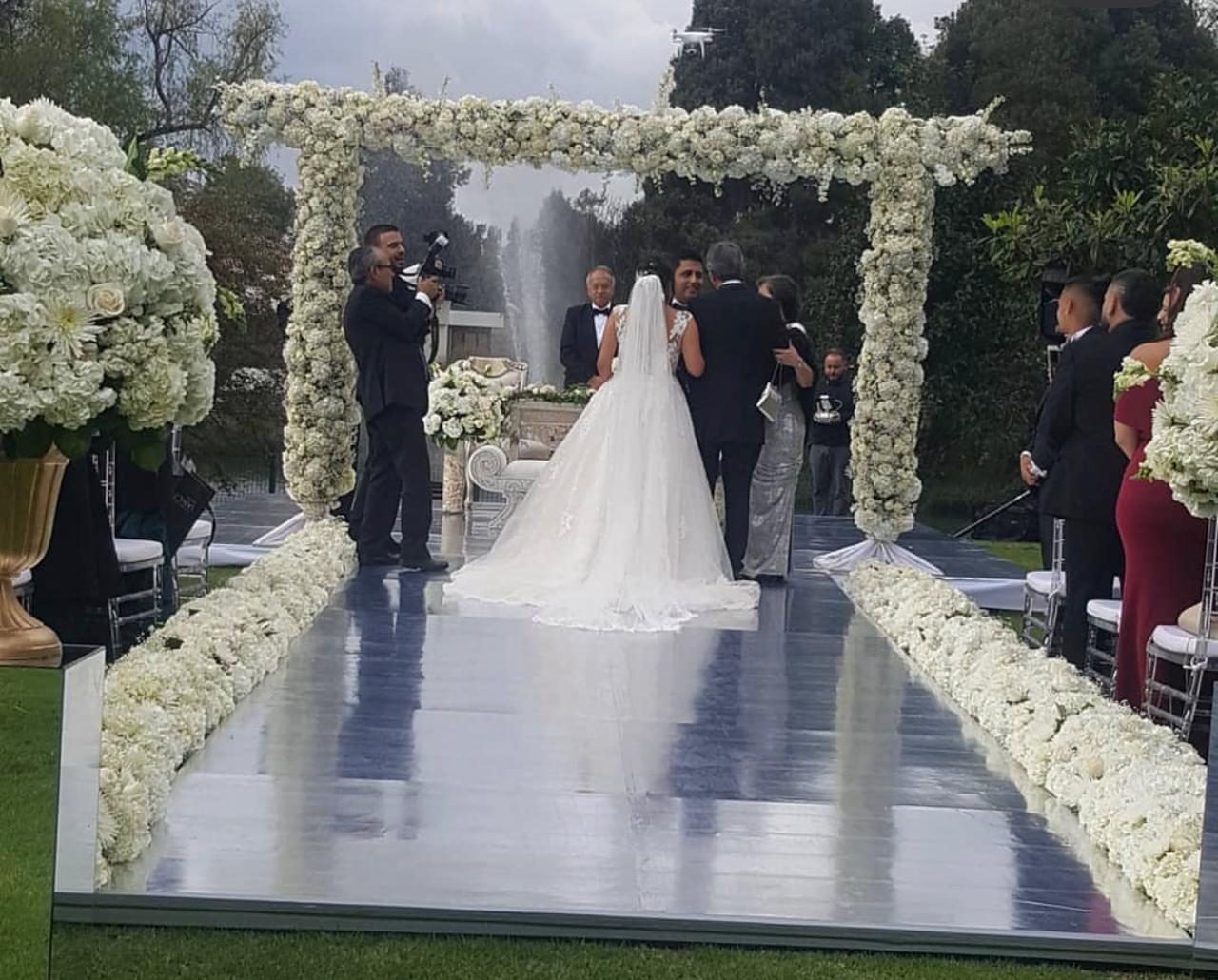 Ceremonia en un jardín con pasillo de flores blancas y fuente