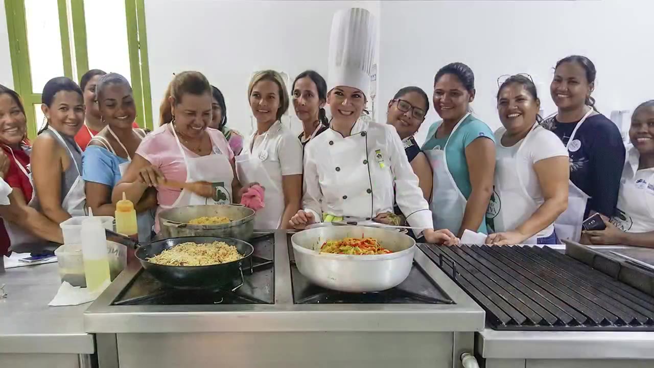 Grupo de alumnas con delantal en una clase de cocina junto a la chef